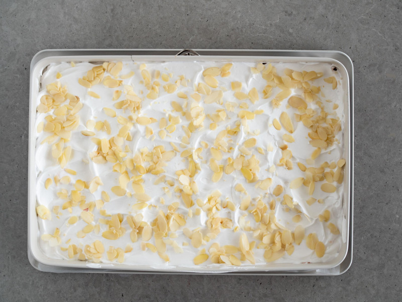 ciasto z rabarbarem i bezą posypane płatkami migdałów przed upieczeniem