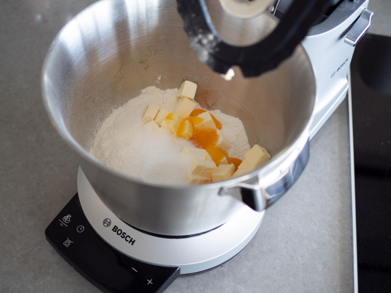 mąka, proszek do pieczenia, masło pokrojone w kostkę, cukier i żółtka w misie robota kuchennego marki Bosch