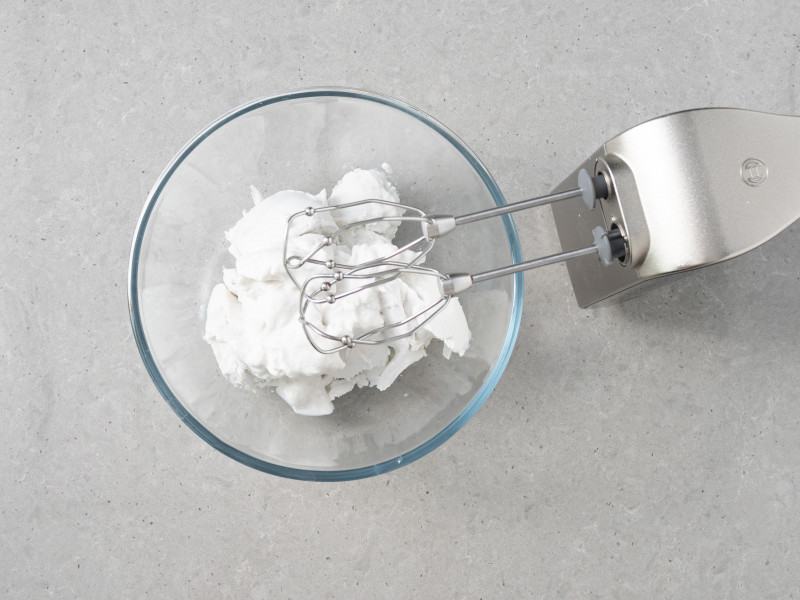 Śmietanka kokosowa w miseczce i mikser ręczny.