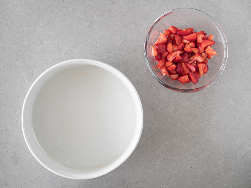 Okr膮g艂a forma o 艣rednicy 25 cm wysmarowana olejem kokosowym. Obok truskawki w miseczce.