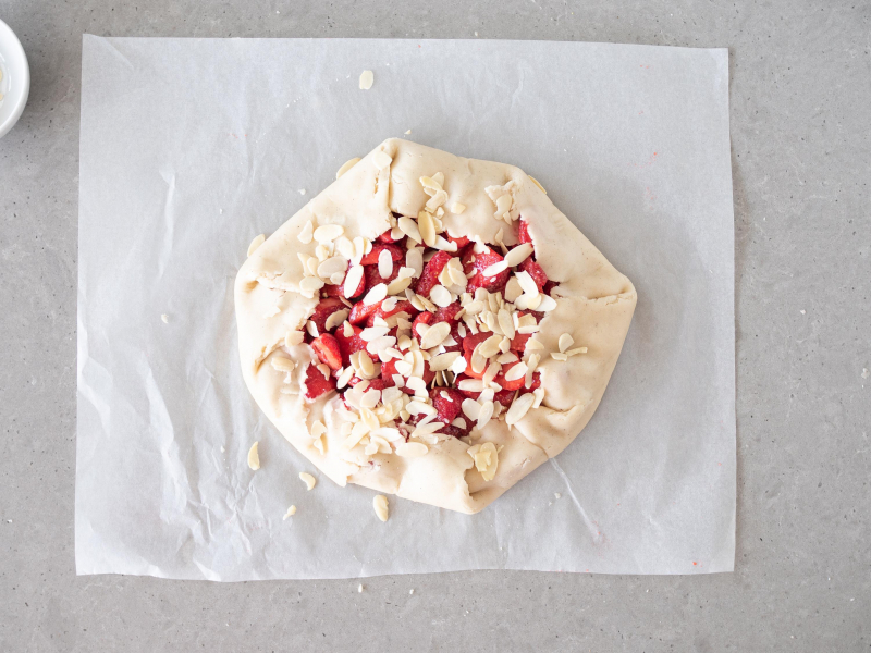 Wegańskie galette z truskawkami, posypane płatkami migdałów, jeszcze przed upieczeniem.