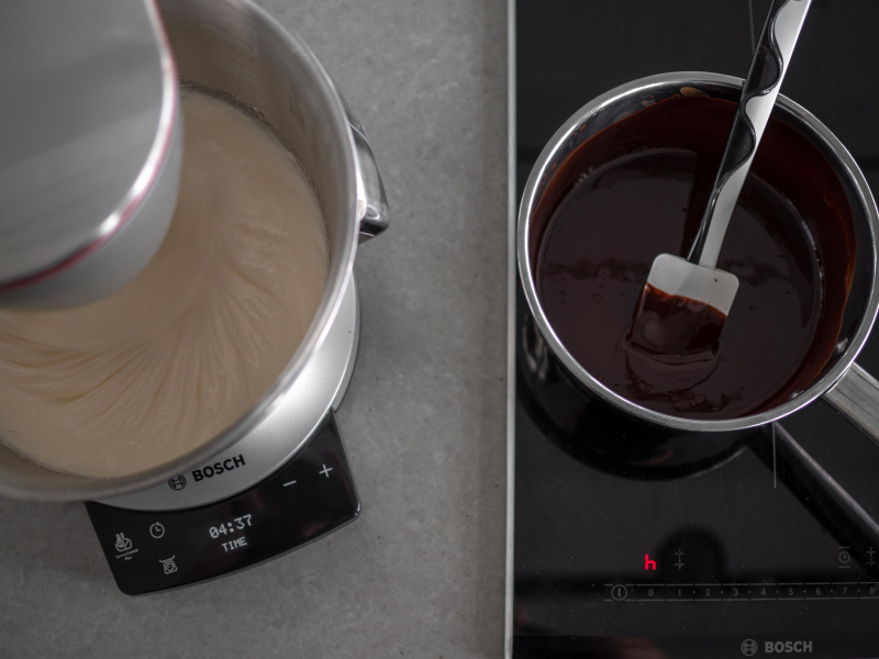 na blacie robot kuchenny bosch z masą jajeczną, obok rondelek z czekoladą na płycie indukcyjnej BOSCH
