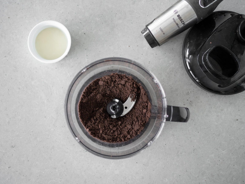 W pojemniku malaksera pokruszone ciasteczka oreo. Obok rozpuszczony olej kokosowy.