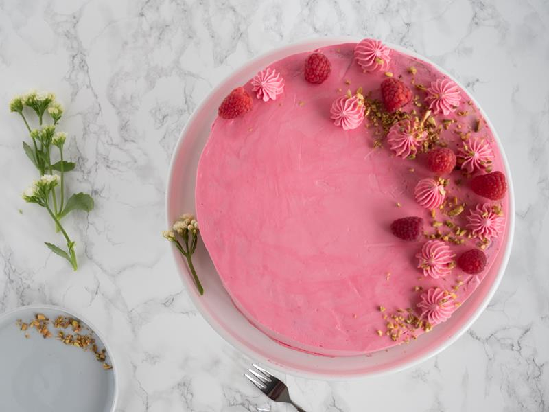 tort malinowy udekorowany malinami i pistacjami