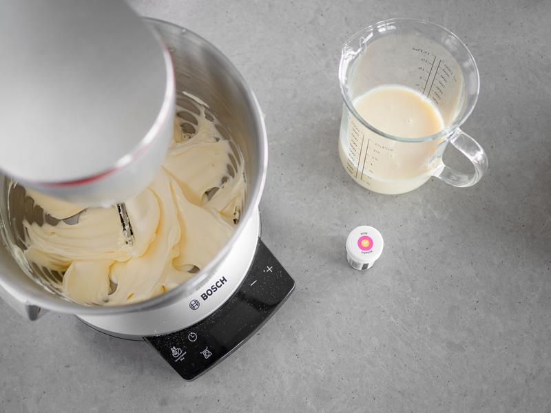 w misie robota ucierane masło obok w naczyniu mleko skondensowane i różowy barwnik Wilton