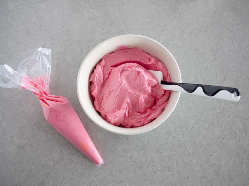 w miseczce różowy krem maślany do tynkowania tortu