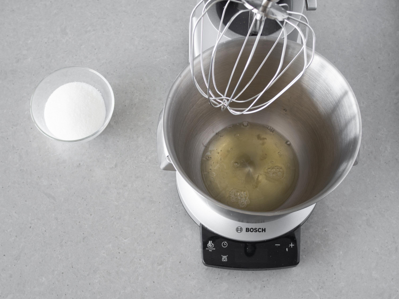 Biała w misie robota kuchennego firmy Bosch. Obok w miseczce cukier.