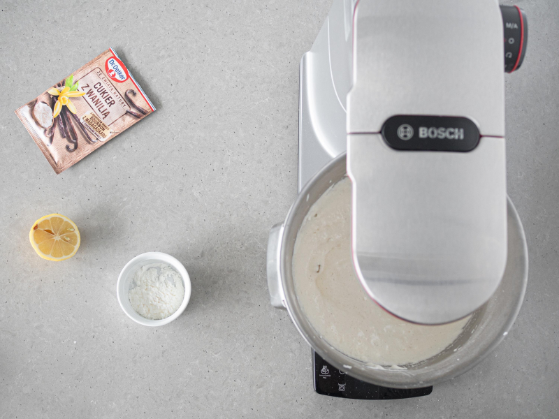 W misie robota kuchennego masa z białek, cukru i żółtek. Obok cukier z wanilią Dr. Oetkera, cytryna i mąka ziemniaczana.