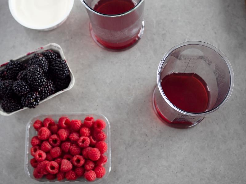 na blacie maliny, jeżyny i w naczyniach rozpuszczona galaretka malinowa
