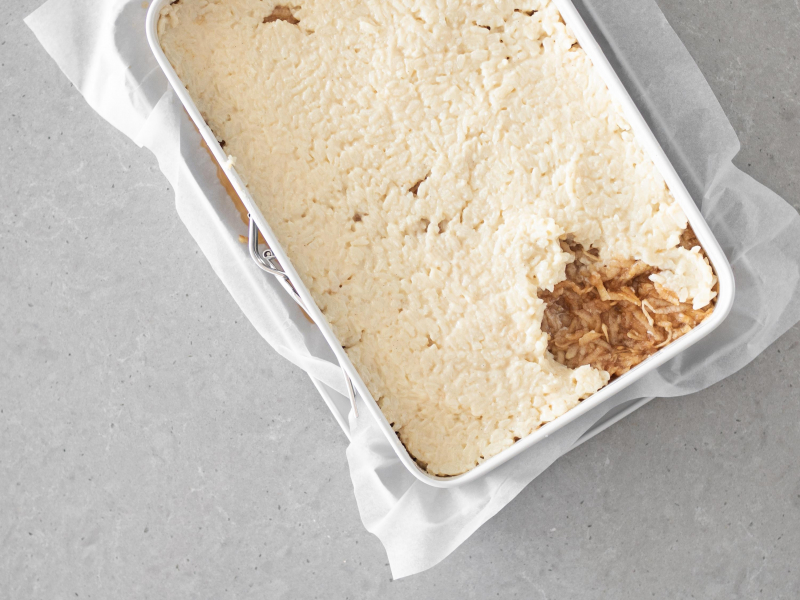 Nakładanie kolejnej warstwy ugotowanego ryżu, na starte jabłka.