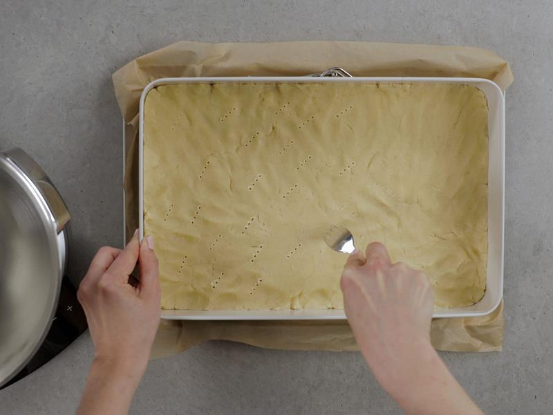 na blacie forma do pieczenia z wyłożonych spodem ciasta nakłuwanego widelcem