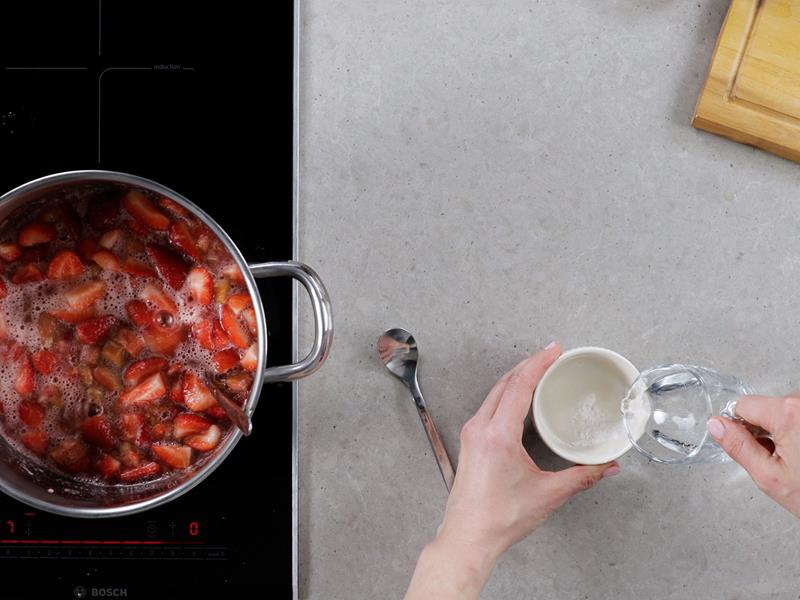 garnek z gotującymi się owocami obok mieszana skrobia z wodą