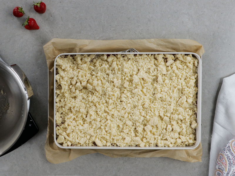 przygotowane ciasto kruche z rabarbarem i truskawka przykryte kruszonką