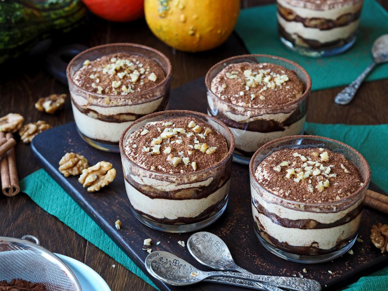 dyniowe tiramisu na bazie kremu z mascarpone, śmietanki i puree z dyni, przekładanego biszkoptami zanurzanymi z mieszance kawy i amaretto, posypane kakao i udekorowane posiekanymi orzechami włoskimi, tiramisu w szklankach na tacy - wszystkiego słodkiego
