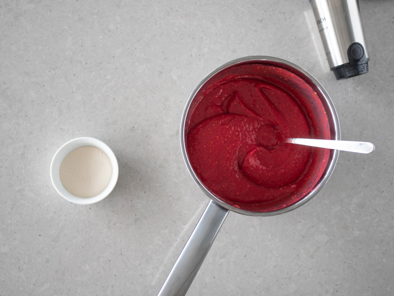 Zblendowane maliny w garnku. Obok w miseczce agar.