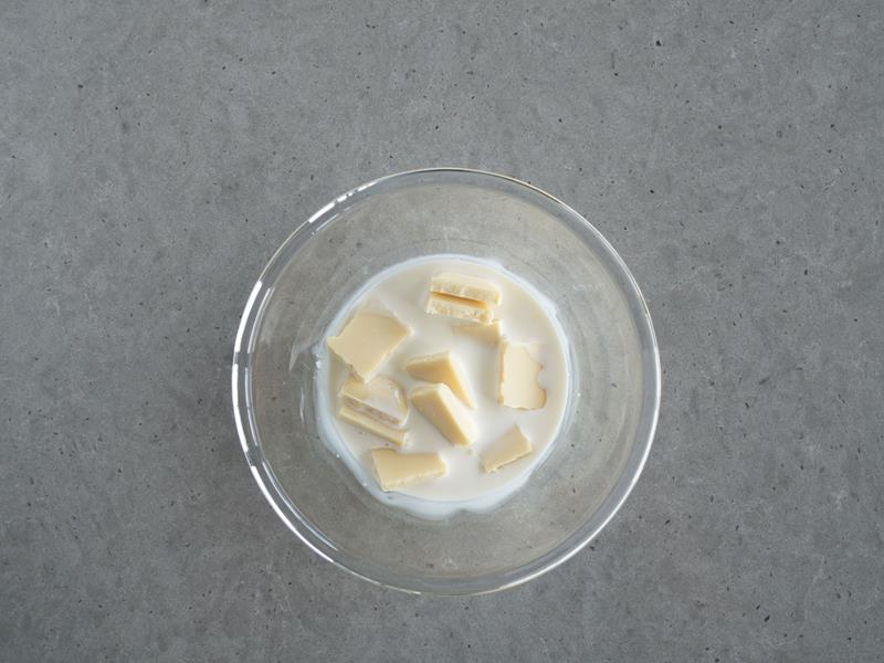 w szklanej miseczce kawałki białej czekolady ze śmietanką