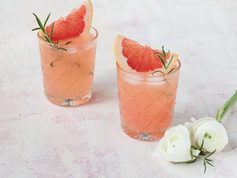 Lemoniada grejfrutowa z wanili膮 i rozmarynem w dw贸ch szklankach podana z kostkami lodu, cz膮stk膮 grapefruita i 艂ody偶k膮 rozmarynu - Wszystkiego S艂odkiego