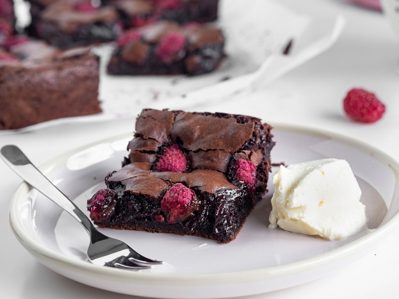 Brownie z malinami na talerzyku z kremem śmietankowym - Wszystkiego Słodkiego