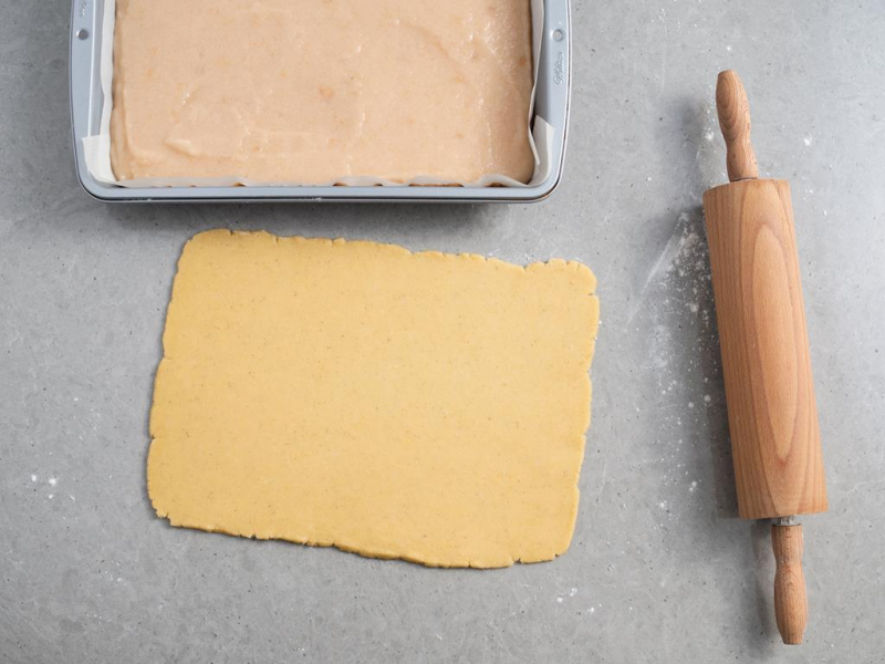 rozwałkowane ciasto półkruche układane na musie jabłkowy