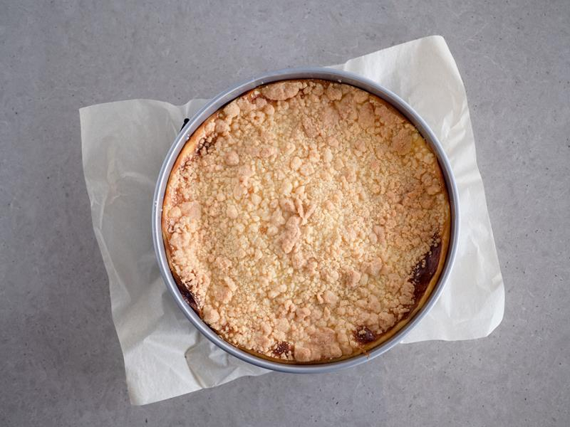 w okrągłej formie upieczona szarlotka z budyniem i kruszonką