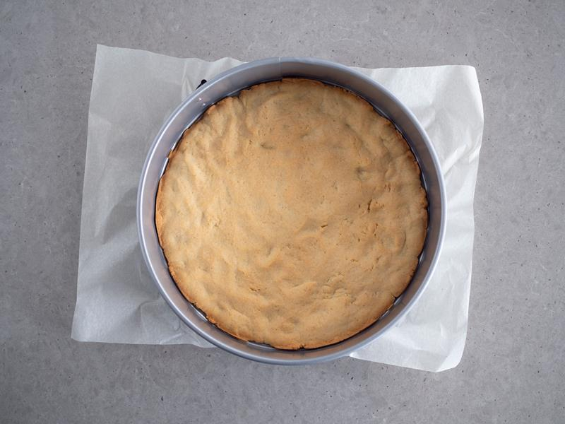 upieczony spód ciasta kruchego na szarlotkę z budyniem w tortownicy wyłożonej papierem do pieczenia