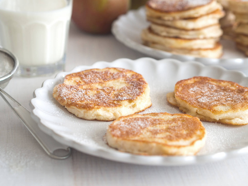 Placuszki z jabłkami i cukrem pudrem na białym talerzyku - Wszystkiego Słodkiego