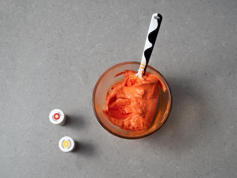 w miseczce krem maślany zabarwiony na pomarańczowo za pomocą barwników spożywczych Wilton