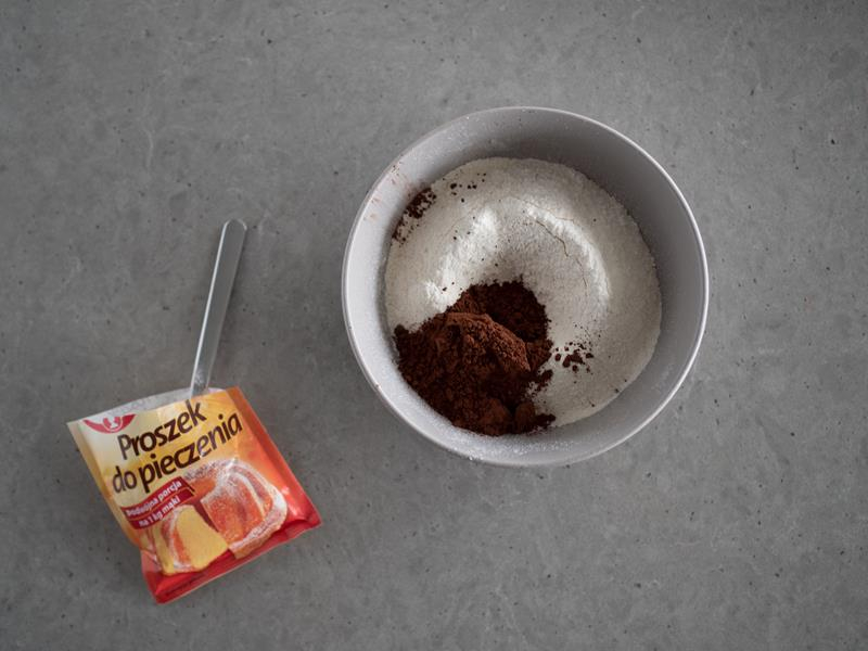 w miseczce przesiana mąka z proszkiem do pieczenia i kakao, obok opakowanie proszku do pieczenia dr. oetkera