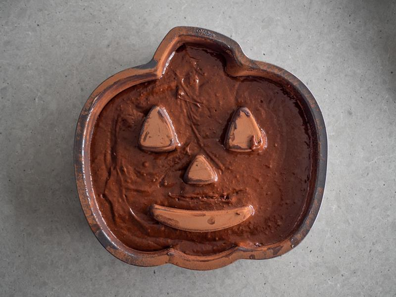 czekoladowe ciasto na halloween przelane do formy w kształcie dyni przed pieczeniem