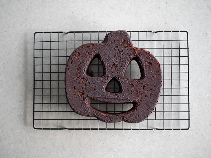 upieczone czekoladowe ciasto na halloween w kształcie strasznej dyni wyjęte z formy i studzące się na kratce