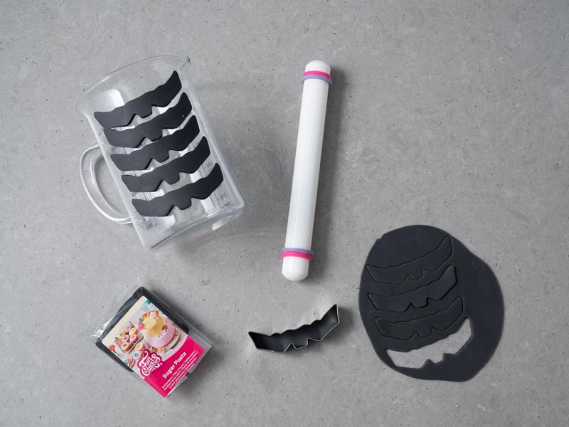 wycięte z masy cukrowej czarne nietoperze, obok wałek do masy cukrowej