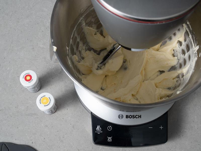 w misie robota kuchennego bosch ucieranie masła na krem maślany, obok barwniki spożywcze Wilton żółty i czerwony