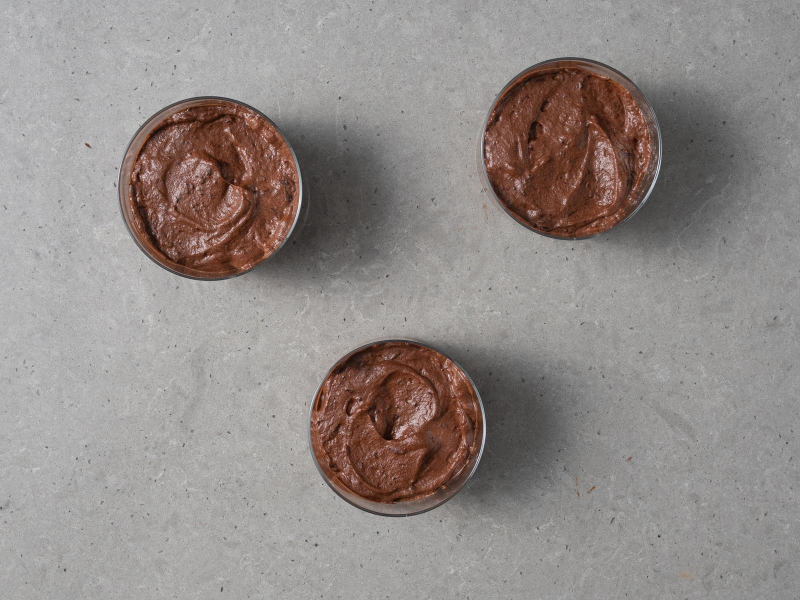 Wegański czekoladowy mus z aquafaby rozłożony do trzech niskich szklaneczek.