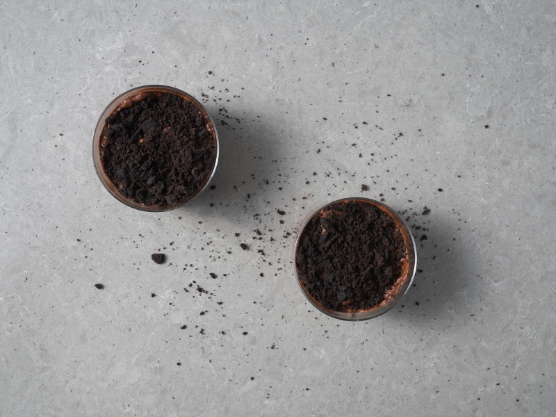 Wegański czekoladowy mus z aquafaby posypany czarnymi pokruszonymi ciasteczkami.