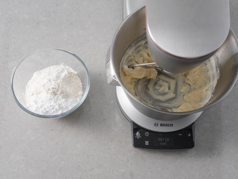 Mąka pszenna ze szczyptą soli w misce. Obok utarty cukier z margaryną wegańską.