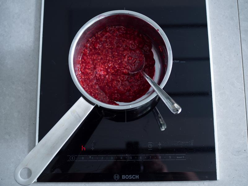 maliny ugotowane z cukrem i zagęszczone mąką ziemniaczaną w rondelku z łyżką na płycie kuchenki