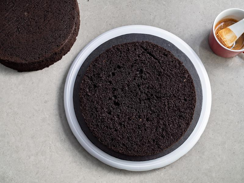 dwa blaty czarnego biszkoptu oraz kubek z kawą i silikonowym pędzelkiem do nasączenia
