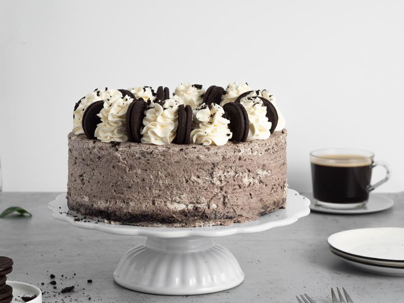 tort oreo obłożone kremem śmietankowym z ciasteczkami oreo, ozdobiony bitą śmietanką oraz ciastkami oreo, podany na paterze