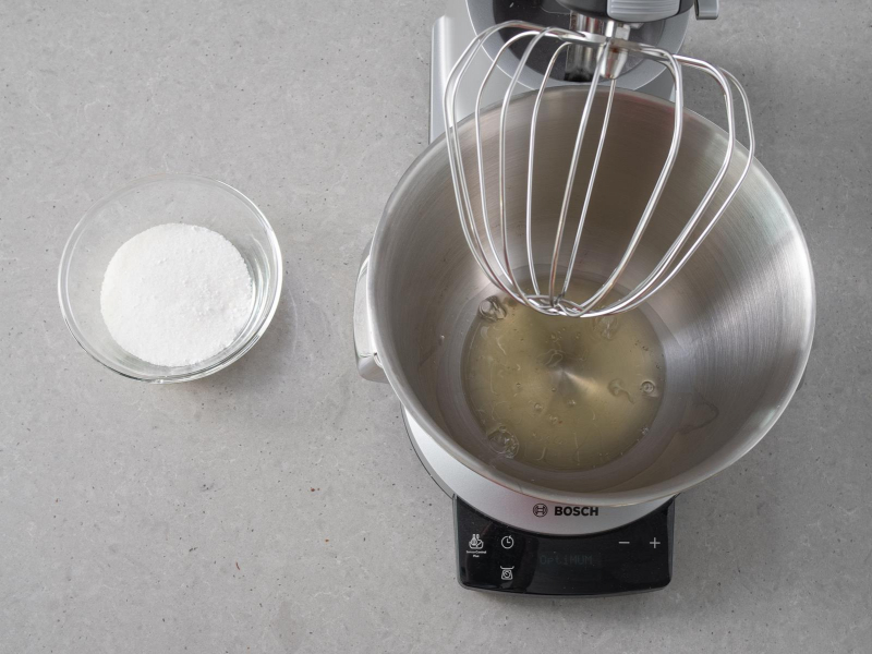 Misa robota kuchennego z białkiem. Obok cukier w miseczce.
