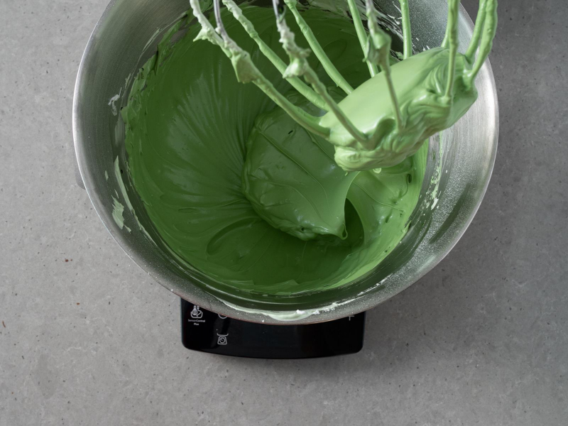 Ubita beza z wymieszanym zielonym barwnikiem firmy Wilton w misie robota kuchennego marki bosch.