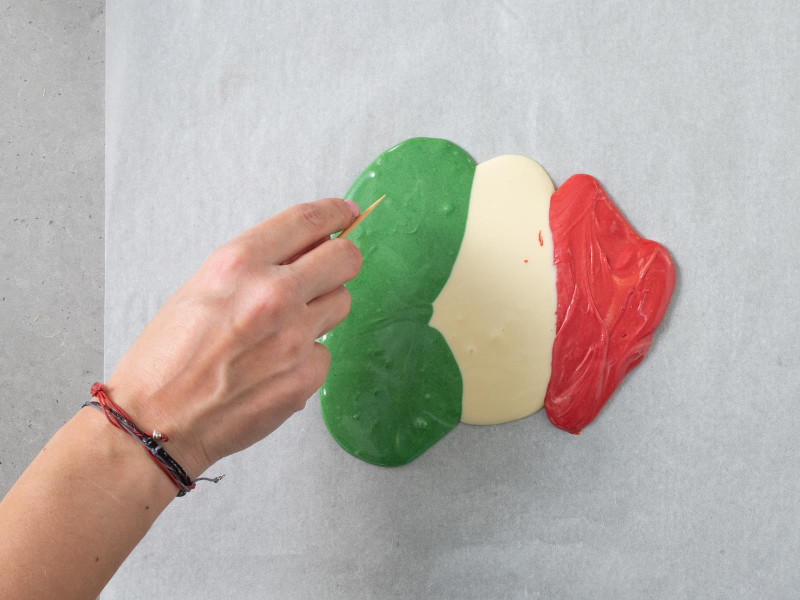 rozlana na papierze do pieczenia czekolada w trzech kolorach: zielonym, białym i czerwonym