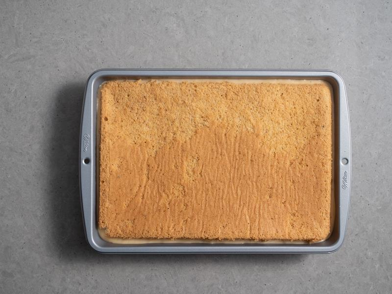 drugi blat biszkoptu toffi wyłożony na warstwę z pierwszym blatem i kremem budyniowym toffi w formie do pieczenia wilton