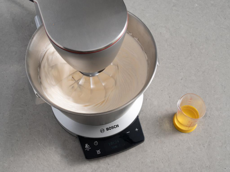 białka ubite z cukrem i żółtkami w misie robota kuchennego, obok pojemniczek z olejem, Robot kuchenny Bosch Optimum MUM9BX5S65
