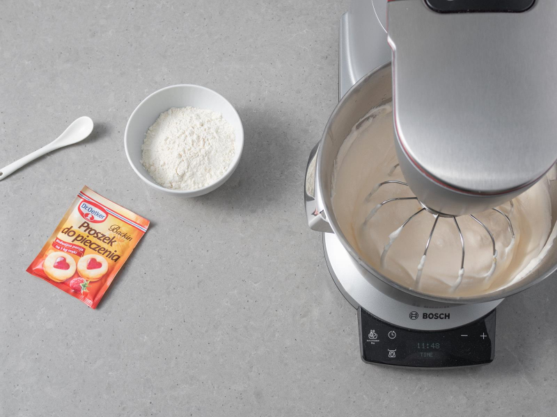 W misie miksera bosch wymieszane ubite białka z żółtkami. Obok opakowanie proszku do pieczenia dr. oetkera, mąka pszenna w miseczce oraz sól na łyżeczce.