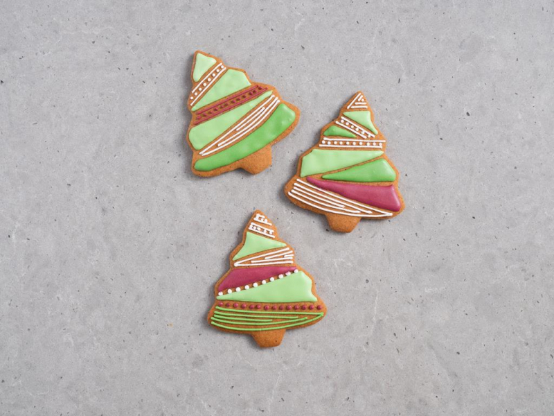 gotowe pierniczki w kształcie choinek udekorowane różnymi odcieniami lukru