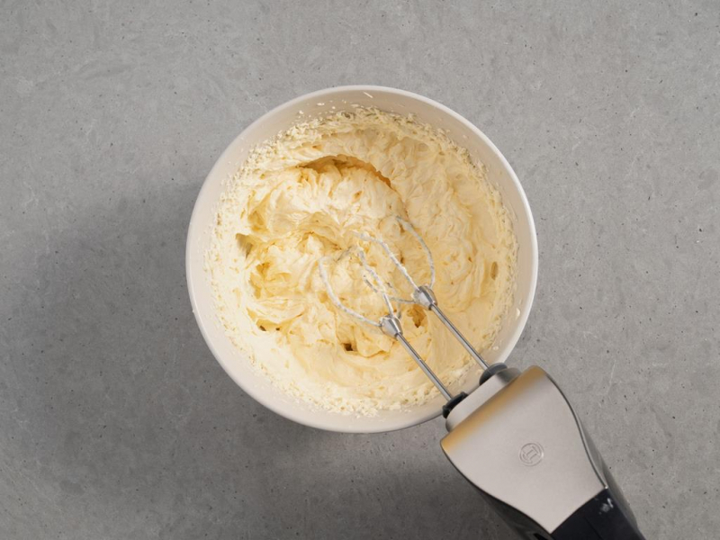 krem budyniowy z masłem w misce ubijany za pomocą miksera ręcznego