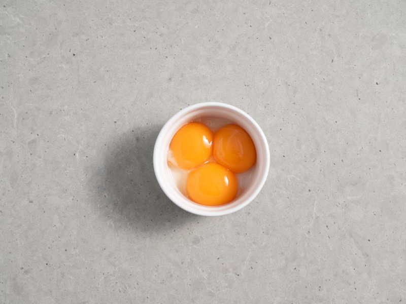 trzy żółtka do biszkoptu w małej miseczce