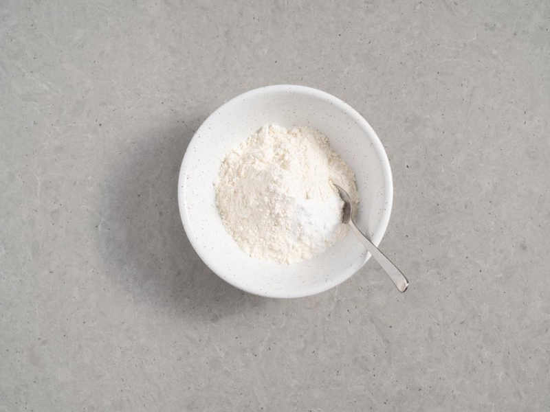 mąka z proszkiem do pieczenia w miseczce z łyżeczką