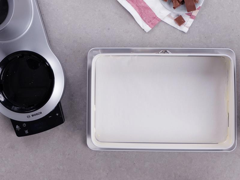 na blacie duża prostokątna forma do pieczenia z odpinanym rantem z serii Black Trend od Dr. Oetkera, z dnem wyłożonym papierem do pieczenia i bokami posmarowanymi masłem