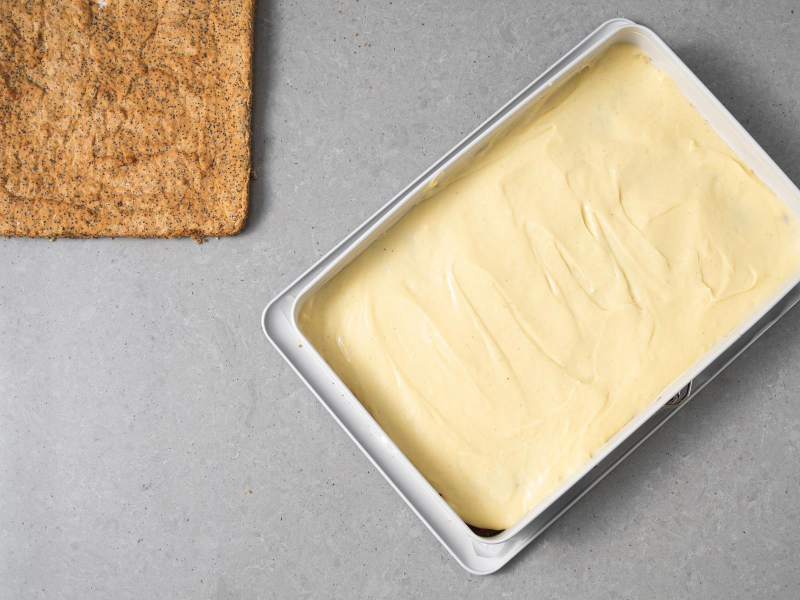 krem budyniowy rozsmarowany na dolnym blacie makowym